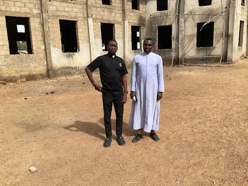 Father Reuben Shaba, left, and Father Dauda Musa Bahago stand in front of the facade of Holy Family Catholic Church under construction in Adunu in Niger State, Nigeria. Courtesy of Father Dauda Musa Bahago